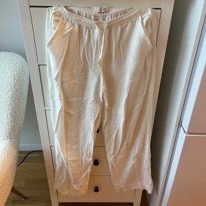 Vita linnebyxor från Nelly XS - Säljer ett par fräscha vita linnebyxor från Nelly i storlek XS. Byxorna har elastisk midja med snörning, sidfickor och en bakficka. 