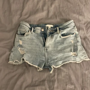 Ljusa jeansshorts med slitningar - Säljer ett par ljusa jeansshorts med slitningar och fransiga kanter. (Frakt ingår)