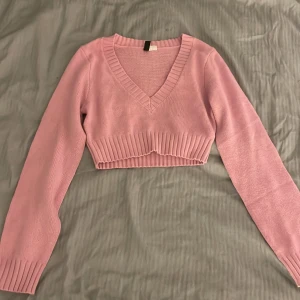 Rosa croppad stickad tröja - Säljer en tunn stickad magtröja med v-ringning och långa ärmar. Knappt andvänd! (Frakt ingår)💓