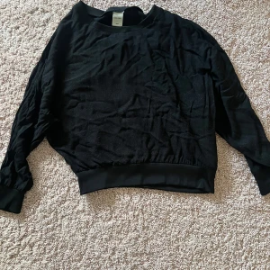 Svart tröja med ribbade muddar - Säljer en svart tröja med ribbade muddar vid ärmslut och nederkant. Tröjan har en lös passform och långa ärmar, perfekt för en avslappnad stil. Sitter tight i ärmslut och nederkant. Passar bra till både jeans och kjol. Tröjan är lite glittrig typ men de Synns bara ibland. Tröjan är i 38 men enligt mig är den mindre och passar typ 34-38