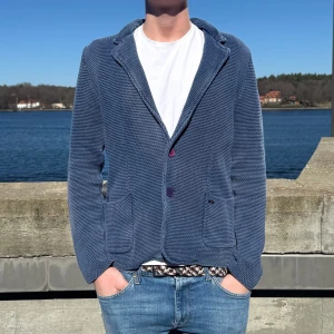 Blå stickad cardigan - Blå stickad cardigan jacka med två framfickor och knappar. 