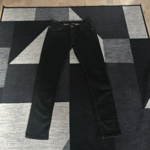 Svarta jeans från Emporio Armani - Snygga svarta jeans från Emporio Armani med klassisk femficksdesign och logotypdetalj på bakfickan. Perfekta för en stilren look. De har en rak passform och är tillverkade i ett slitstarkt material.