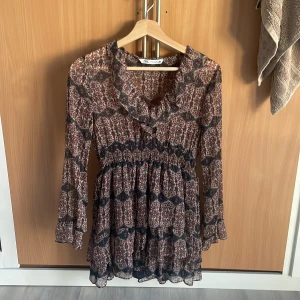 Mönstrad klänning från Zara - Säljer min klänning från Zara som ej säljs längre med långa ärmar och volangdetaljer. Klänningen har ett midjeband och ett vackert blom liknande mönster i rött och blått. Perfekt till en varm sommar dag💕 skriv om det är något du funderar på💕
