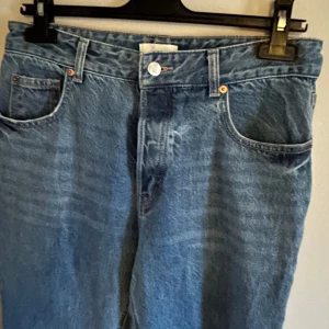 Blå jeans från H&M - Säljer ett par klassiska blå jeans från H&M. De har en normal passform med fem fickor och knappgylf. Perfekta för en avslappnad stil.
