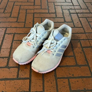 Adidas sneakers - Adidas träningsskor med rosa sula, använda en del och hade behövt tvättas om man vill ha dem vita igen, men inga hål eller slitage så dem är fortfarande bekväma och bra