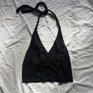 Svart halterneck topp - Snygg svart halterneck topp med djup v-ringning. Toppen knyts i nacken och har en croppad passform.