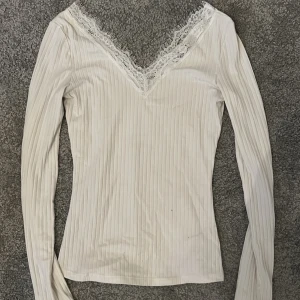 Vit ribbad långärmad topp med spetsdetalj - Säljer en vit långärmad tröja då jag inte använder den längre, den är använd några gånger men inga tydliga tecken på användning 
