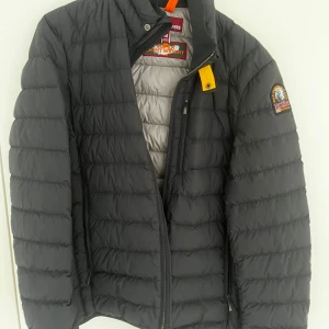 Svart pufferjacka från Parajumpers - Säljer en svart pufferjacka från Parajumpers. Jackan är superlätt och har en dragkedja framtill. Den har ett märke på ärmen och är perfekt för kyligare dagar. Passar bra för både höst och vår. Den är helt oanvänd, kvitto, tags och extra knappar till kommer. Ny pris ca 5000kr. Mitt pris 3000, ej hugget i sten vid snabb affär