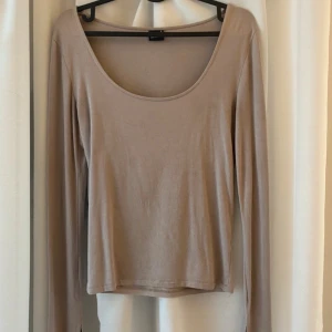 Långärmad tröja med slits  - Säljer en beige långärmad topp från Gina Tricot i storlek S. Toppen har en rundad halsringning, materialet är mjukt och bekvämt. Den har en slits vid ärmslutet.