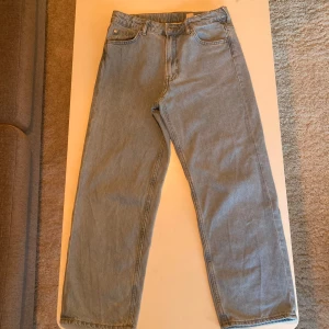 Baggy jeansbyxor från H&M - Säljer ett par blå jeansbyxor från H&M i baggy fit med justerbar midja. Perfekta för en avslappnad stil. Klassisk design med fem fickor och knappgylf. Kolla gärna in mina andra annonser!