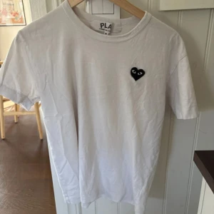 Vit t-shirt från Play Comme des Garçons - Vit t-shirt från Play Comme des Garçons med ett litet svart hjärta med ögon broderat på bröstet. Säljer då den var för kort. Fint skick på den. Hör gärna av vid fler funderingar 