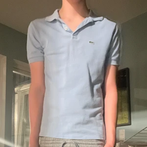 Ljusblå pikétröja från Lacoste - Säljer en ljus blå piké från Lacoste. Pga för har inte kommit till användning, funkar jätte bra att ha på sig den vid varma dagar på sommaren 