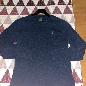 Långärmad raulph lauren tröja - Jag säljer en långärmad raulph lauren tisha (funkar även som sweatshirt) i väldigt fin blå grå färg med vit logga. Den är storlek M men skulle säga att den sitter som en S. tröjan är i fint skick