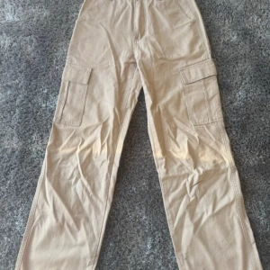 Beiga cargobyxor med raka ben - Säljer ett par beiga cargobyxor med raka ben och stora fickor på sidorna. 