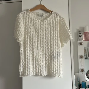 Vit spetstopp från AWARE - Säljer en vit topp från AWARE med korta ärmar och vackert spetsmönster. Toppen har en rak passform och är tillverkad i ett lätt och luftigt material, perfekt för varmare dagar. (Storleken står ej med men den är i storlek S!🌷🧚🏻)