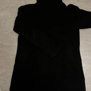 Svart stickad tröja - Mysig svart stickad tröja med polokrage och långa ärmar. Perfekt för kyligare dagar och enkel att styla med boots eller sneakers. Mjuk och skön känsla mot huden. Säljer den billigt då jag vill bli av med den samt att den är nopprig!