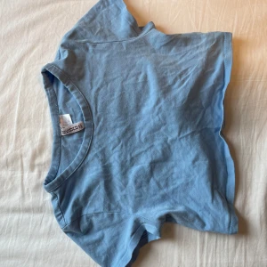ljusblå croppad t-shirt - baby tee magtröja från h&m divided! tröjan har korta ärmar som slutar ungefär mitt på axeln. observera att tröjan är kort, även för en magtröja, så den är bättre passad för någon med en mindre byst.