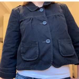 Svart kavajjacka med fickor - Säljer en svart kavajjacka med tre knappar framtill och två stora fickor. Jackan har en klassisk krage och synliga sömmar som ger en cool touch. Passar perfekt till jeans eller kjol.