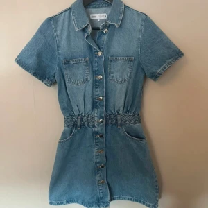 Kort jeansklänning från Zara - Säljer en snygg kort jeansklänning från Zara med korta ärmar och knappar framtill! Skitsnygg nu till sommaren 💕💕