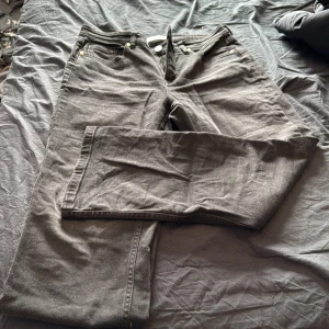 Svarta jeansbyxor med raka ben  - Säljer ett par svarta jeansbyxor med klassisk femficksdesign och raka ben. Byxorna har knapp- och dragkedjegylf samt nitar vid fickorna. Perfekta för en stilren och enkel look.