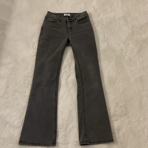 Grå bootcut jeans från Lindex - Säljer ett par gråa bootcut jeans från Lindex. Jeansen har klassisk femficksdesign, normal passform upptill och utsvängda ben. Perfekta för dig som gillar en retroinspirerad look. Materialet är mjukt och bekvämt.