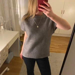 Grå kortärmad tröja från Zara - Säljer en enkel och stilren grå tröja från Zara. Tröjan har korta ärmar, rund halsringning och är gjord i ett mjukt material som känns lite ulligt. Så snygg! 