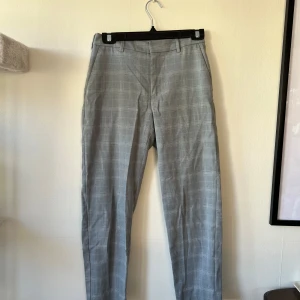Grå rutiga kostymbyxor - Snygga grå kostymbyxor med vitt rutmönster. Ca storlek 34. Något noppriga därav priset.