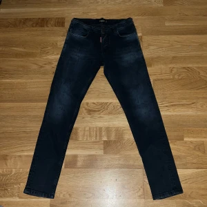 Dsquared blåa jeans !!ÄR VÄRDA 4000-6000kr!! - Säljer ett par mörkblå jeans från Dsquared2 med klassisk femficksdesign och rakt snitt. Jeansen har en snygg tvätt och detaljerad röd läderpatch bak i midjan. Perfekta för dig som gillar stilrena och trendiga jeans.