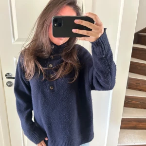 Polotröja från Zara  - Mysig mörkblå stickad polotröja med hög krage och fem knappar framtill. Tröjan har lång ärm och ribbade muddar vid ärmslut och nederkant. Perfekt för kyliga dagar och enkel att styla till jeans eller kjol. Köpt på Zara 