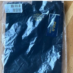 Svart t-shirt från Polo Ralph Lauren - Säljer en klassisk svart t-shirt från Polo Ralph Lauren. T-shirten har rund hals och är kortärmad, perfekt för en stilren och enkel look. Ikonisk logga på bröstet. Passar till det mesta och är riktigt skön att bära.