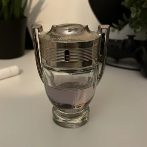 Paco Rabanne Invictus Eau de Toilette 50 ml - Säljer en Paco Rabanne Invictus Eau de Toilette i 50 ml flaska. Parfymen kommer i en ikonisk troféformad glasflaska med silverfärgat lock och detaljer. Doften är fräsch och sportig, perfekt för dig som gillar moderna och energiska parfymer.