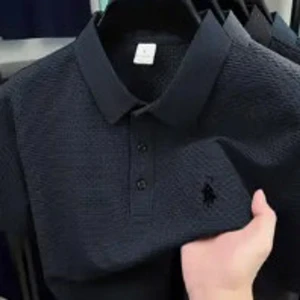 Mörkblå pikétröja från Polo Ralph Lauren - Snygg mörkblå pikétröja med klassisk krage och knappar framtill. Tröjan har ett diskret mönster i tyget och den ikoniska broderade loggan på bröstet. Perfekt för en stilren och avslappnad look.