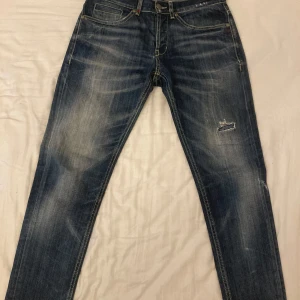 Dondup GEORGE - Säljer ett par blå jeansbyxor från Dondup, modell GEORGE. Byxorna har klassisk femficksdesign, slitningar och en liten slitning på ena benet. Snygga kontrastsömmar och unika detaljer på bakfickan med röd söm och tryck. Skriv vid minsta funderingar.