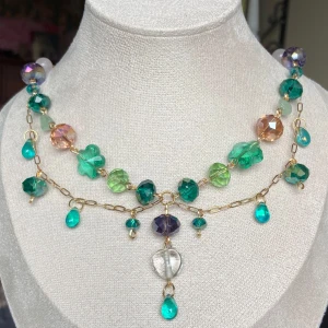 🧚Färgglatt halsband med glaspärlor och guldfärgad kedja🧚 - Unikt halsband med stora glaspärlor i grönt, blått, lila och transparent. Kedjan är guldfärgad och dekorerad med droppformade och blommiga pärlor. Perfekt statement-piece för dig som gillar färg och lekfull design.
