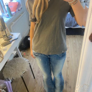 Grågrön t-shirt från Zara - Säljer en enkel och stilren grågrön t-shirt från Zara. Perfekt för en avslappnad look. T-shirten är kortärmad och gjord i bomull. Endast provad. 