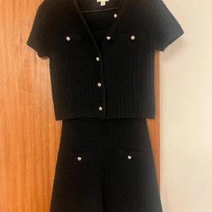 ✨INTRESSEKOLL ✨Svart stickad klänning från H&M - Populära svarta settet från H&M. En klänning & en kofta med korta ärmar och dekorativa knappar i guld. Klänningen har en klassisk design med fickdetaljer framtill. Perfekt för en stilren look. Superfin, passar storlek S också. Kom med bud 🖤