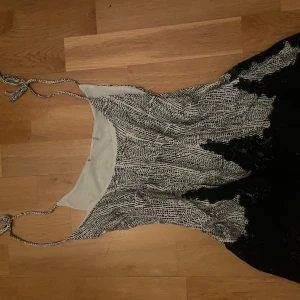 Svartvit ärmlös topp - Säljer en unik svartvit ärmlös topp med tunna axelband och ett abstrakt mönster. Toppen har en lös passform och är perfekt för varma dagar. Har använt 2 ggr så den är i bra skick. Kan användas både som vanligt linne och nattlinne.