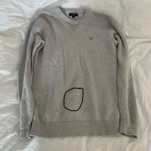 Grå stickad tröja från GANT - Säljer en stilren grå stickad tröja från GANT. Finns ett litet hål i tröjan som är inringat därav så billigt pris.