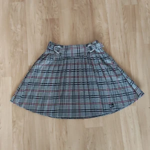 Rutig kjol - Snygg rutig kjol från collection Pimkie i grått, rosa och svart. Kjolen har en klassisk A-linjeform och ett brett midjeband. Tas av och på via en dragkedja på vänster sida. Inköpt på Asos