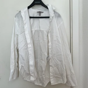 Vit skjorta från H&M - Säljer en klassisk vit skjorta från H&M i storlek XS. Skjortan har långa ärmar och knappar framtill. Perfekt för en stilren look.