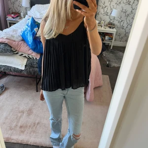 Svart ärmlös topp - Säljer en stilren svart ärmlös topp med v-ringning och plisserad design. Perfekt för en chic och avslappnad look. Passar bra till jeans eller kjol. Storlek 38 men passar mig som brukar ha s-xs