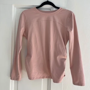 Rosa långärmad tröja från Lululemon - Säljer en stilren rosa långärmad tröja från Lululemon. Tröjan har en unik omlottdesign på baksidan och är tillverkad i ett mjukt och stretchigt material. 