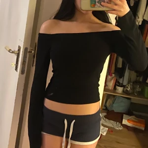 Svart offshoulder topp - Snygg svart offshoulder topp med långa ärmar. Perfekt för en stilren look. Passar bra till både jeans och kjol.