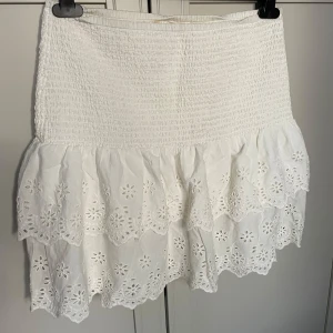 Vit kjol från Holi & Whyte - Säljer en söt vit kjol från Holi & Whyte med volanger och broderade blommor.❤️(Den är aldrig använd)  Kjolen har en elastisk midja för en bekväm passform. Perfekt för varma sommardagar!🌸