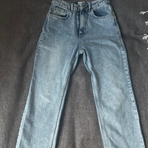 Blå jeansbyxor - Snygga blåa jeansbyxor från NAKD, storlek 34. Med hög midja och klassisk femficksdesign. Byxorna har en rak passform och stängs med dragkedja och knapp. 