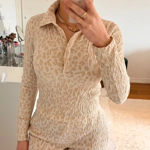 Beige leopardmönstrad tröja och byxa från Zara - Säljer en beige leopardmönstrad tröja från Zara med krage och knappar framtill. Tröjan har långa ärmar och en tight passform, perfekt för en trendig look. Materialet är mjukt och bekvämt. Jag har endast använt den en gång✨