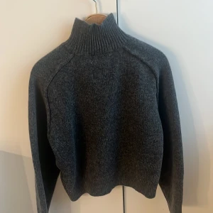 Grå stickad polotröja från H&M - Säljer en mysig grå stickad polotröja från H&M. Tröjan har en hög ribbad krage och långa ärmar, perfekt för kyliga dagar. Den är i en klassisk grå färg som passar till det mesta! Aldrig andvänd☺️