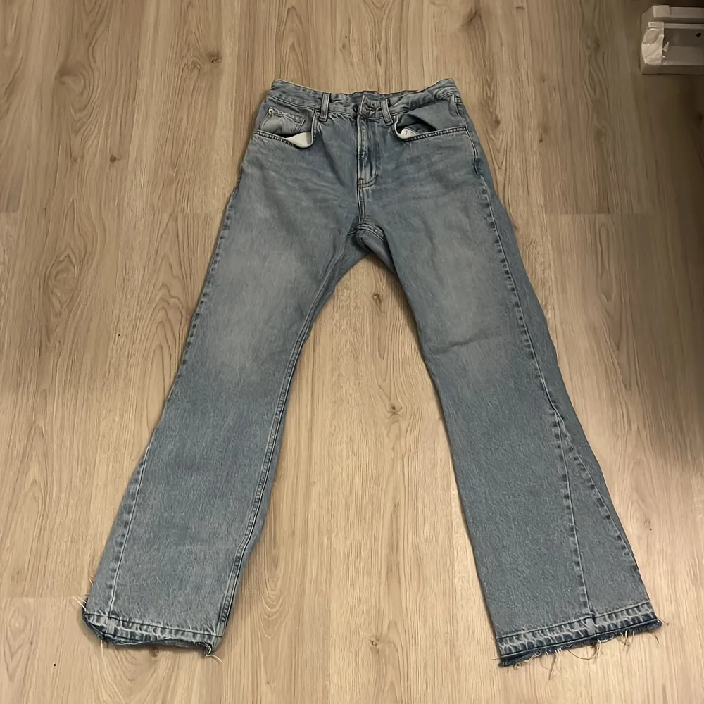 Säljer ett par blå jeans från Zara med en avslappnad passform. Byxorna har en rak stil och fransiga kanter vid bensluten för en trendig look. Perfekta för en casual stil.. Farkut & Housut.