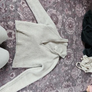 Beige ribbad kofta - Säljer en stilren beige ribbad kofta med långa ärmar. Perfekt för kyligare dagar och lätt att matcha med olika outfits. Ett måste i garderoben för den som gillar enkel och snygg design.