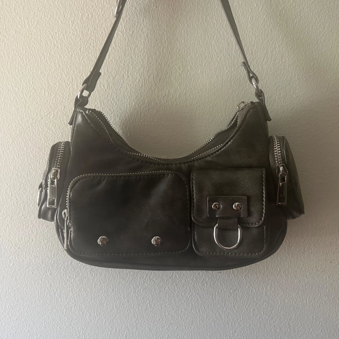 Svart axelväska med fickdetaljer och dragkedjor